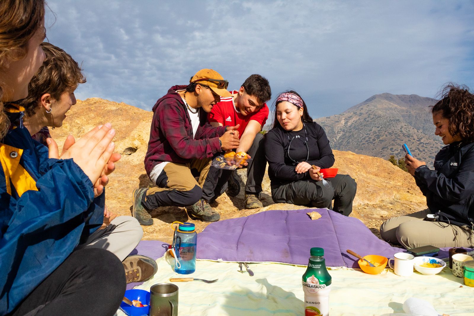 Grupo compartiendo el almuerzo sobre la roca con la cordillera de fondo
