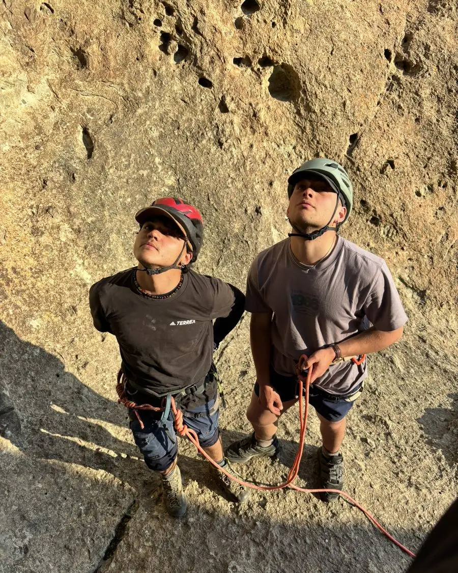 Dos participantes con casco mirando la vía antes de escalar
